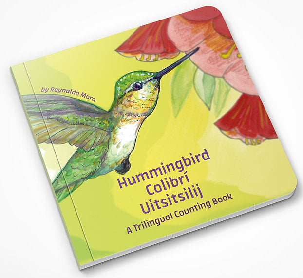 The image shows the cover of Hummingbird Colibri uitsitsilij, a trilingual counting book by Reynaldo Mora. A colorful hummingbird illustration hovers near a flower against a green backdrop, celebrating a rich blend of languages, including Nahuatl.
