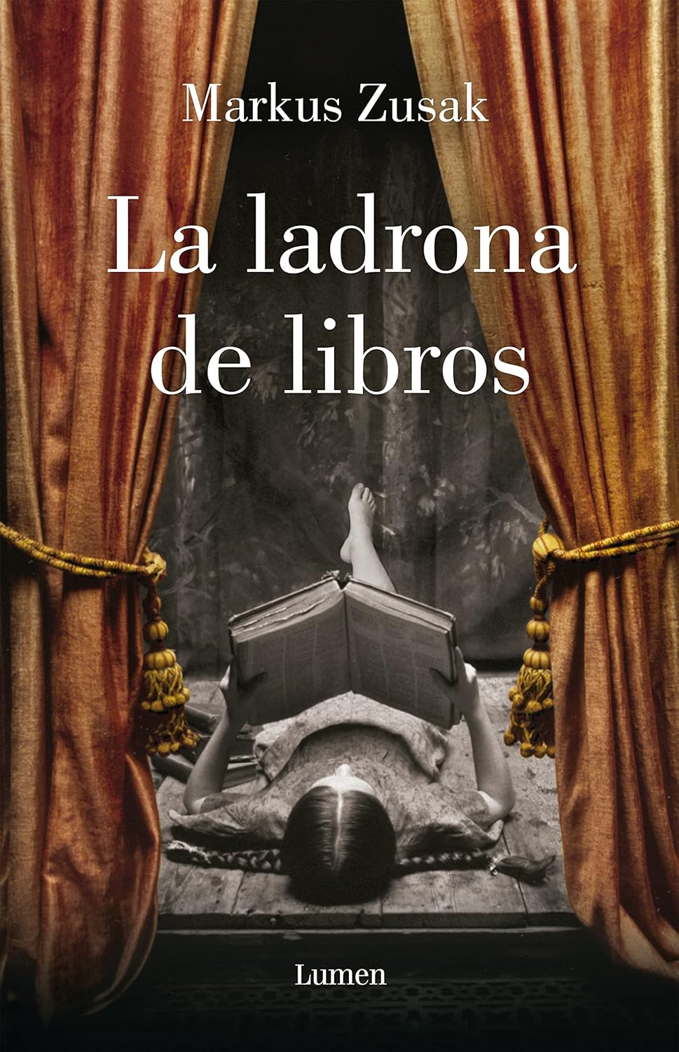 The sepia-toned cover of La Ladrona de Libros / The Book Thief by Markus Zusak features someone lying back, absorbed in a book, framed by red curtains with gold tassels. The authors name and title are prominently displayed in white text.