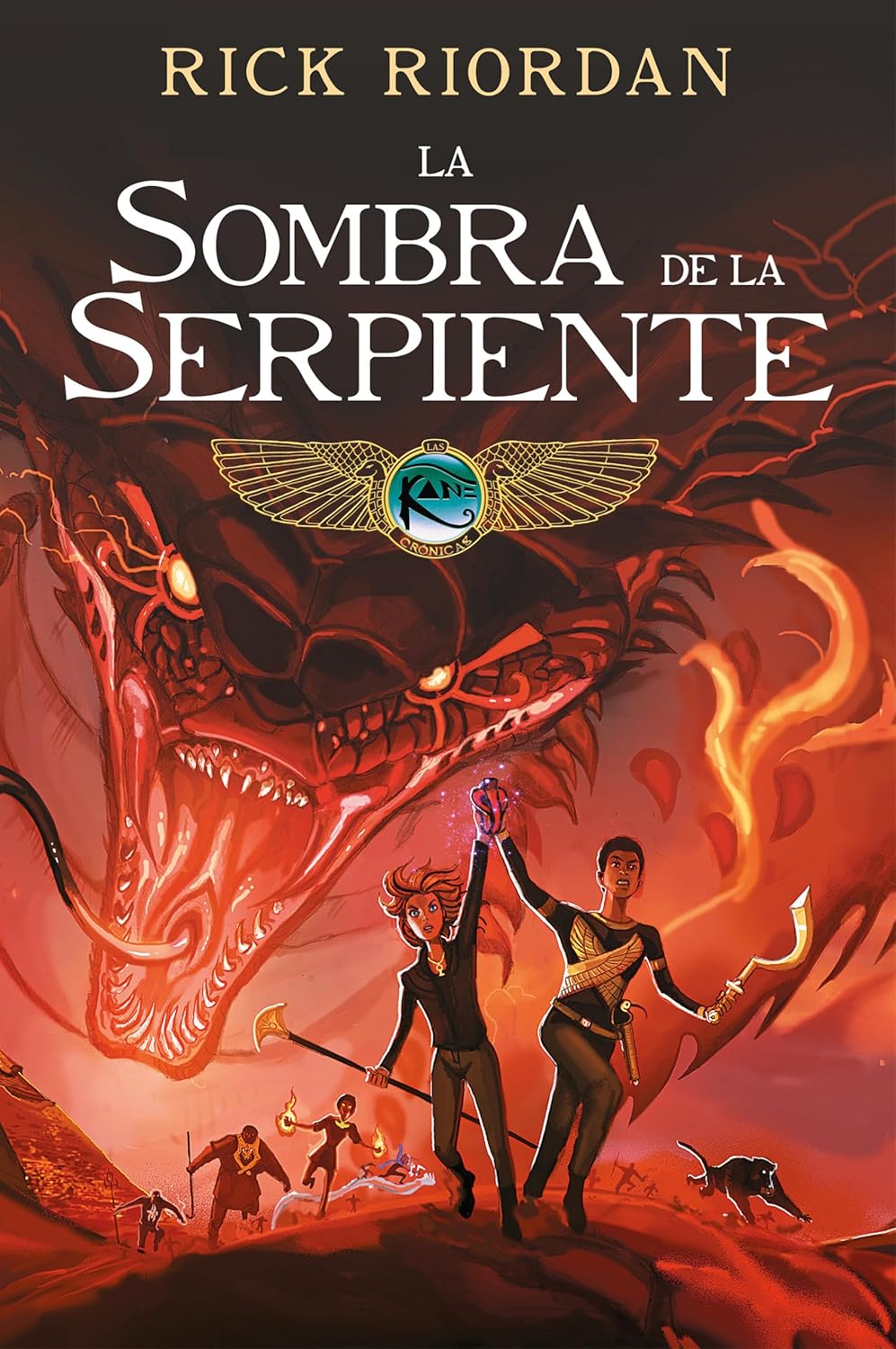 The cover of La Sombra de la Serpiente. Novela Gráfica by Rick Riordan showcases a giant serpent, Apophis, in the background with two confident characters brandishing weapons in the foreground. The fiery, dramatic scene is filled with ancient Egyptian symbols evoking an epic graphic novel style.