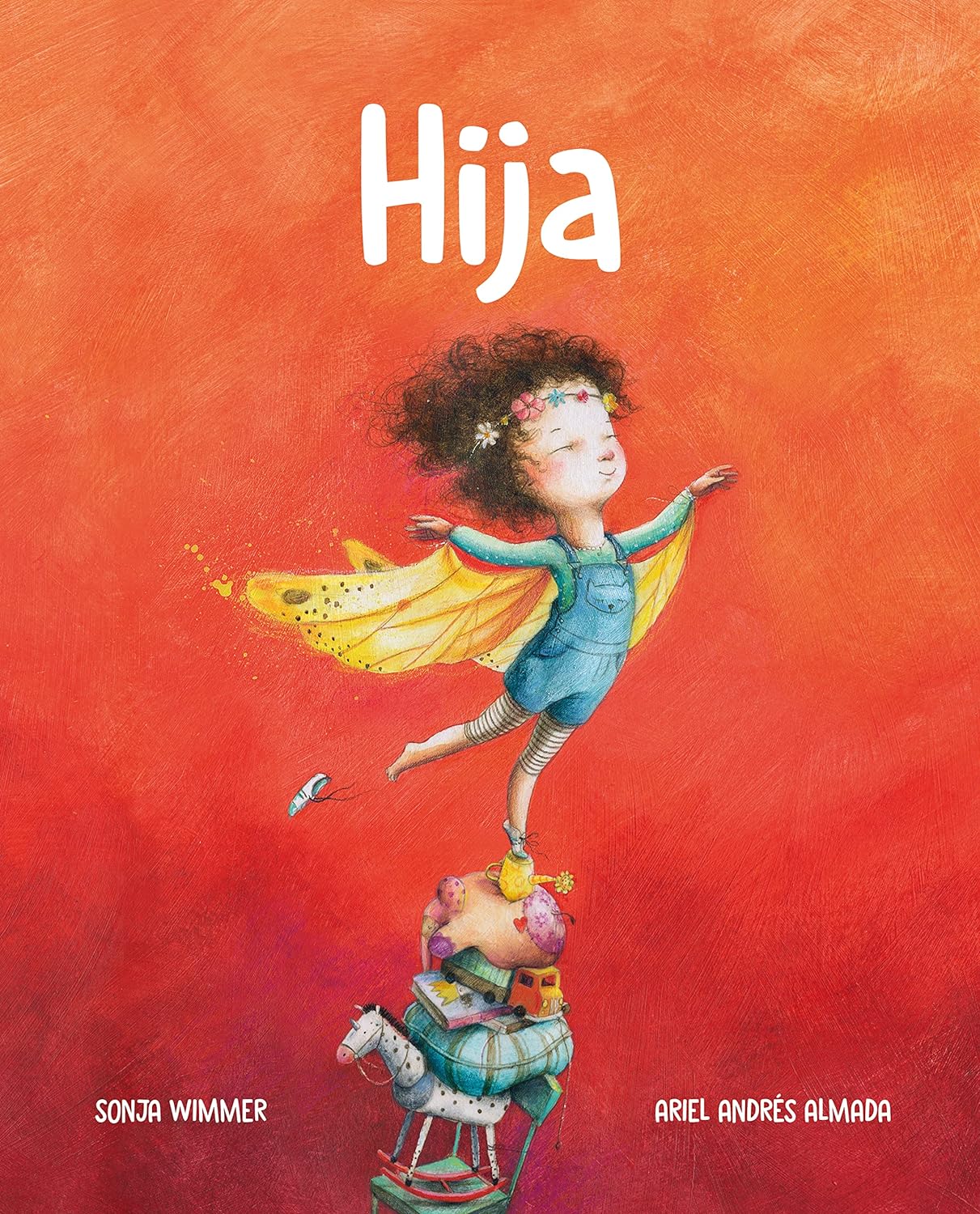 Cover of Hija (Little One) by Sonja Wimmer and Ariel Andrés Almada, featuring a girl with wings on a pile of books, a toy horse, and other items against a vibrant red-orange background, capturing the wonder of child development.
