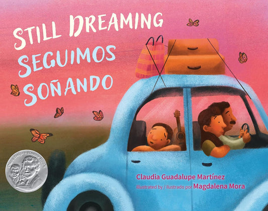 A family in a blue car with luggage, under a pink sky filled with butterflies, captures the essence of Claudia Guadalupe Martínezs childrens book on Mexican Repatriation. Magdalena Moras illustration is adorned with a silver award sticker. Product: Still Dreaming / Seguimos Soñando.