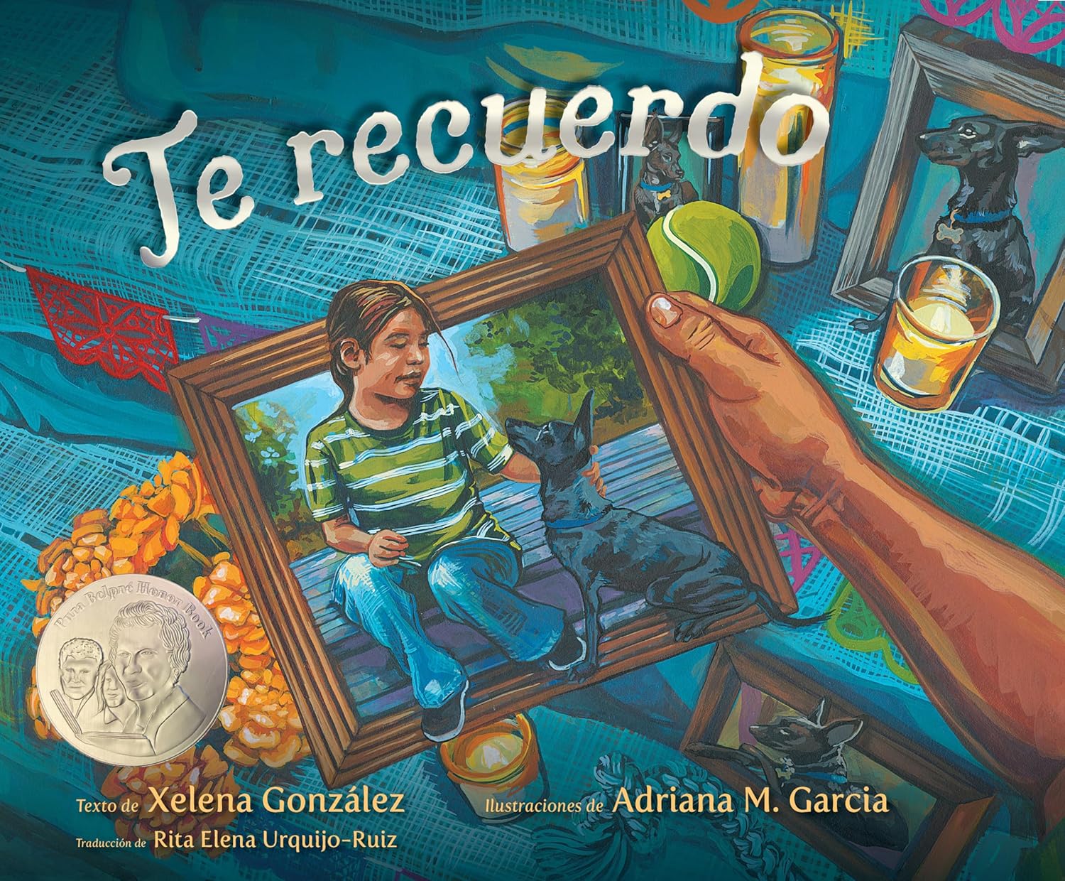 The cover of Te recuerdo (Remembering) displays a vivid illustration similar to an emotional Día de Muertos ofrenda. A hand holds a childs picture with a dog, surrounded by candles, flowers, another dog, and medals—a heartfelt tribute in true Pura Belpré style.