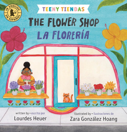 The book The Flower Shop / La Florería by Lourdes Heuer, illustrated by Zara González Hoang, has a vibrant cover showing a woman arranging flowers in a lively shop with a cat. Its adorned with colorful blooms and is bilingual in English and Spanish.